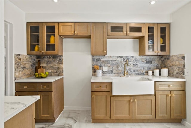 kitchen featuring glass insert cabinets, brown cabinetry, and a sink