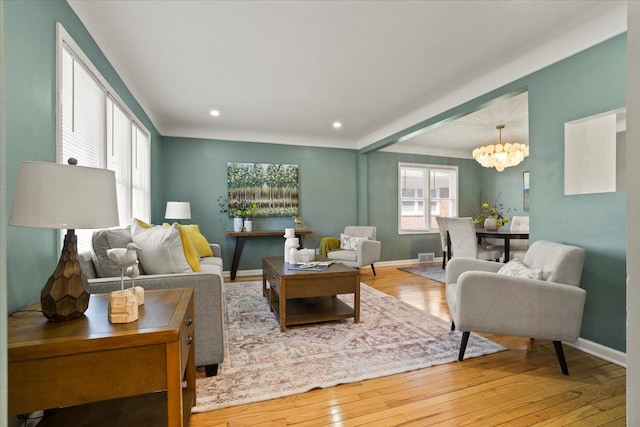 living area featuring an inviting chandelier, baseboards, wood-type flooring, and recessed lighting