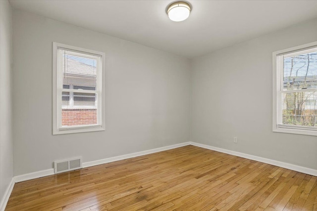 spare room featuring baseboards, visible vents, and light wood-style flooring
