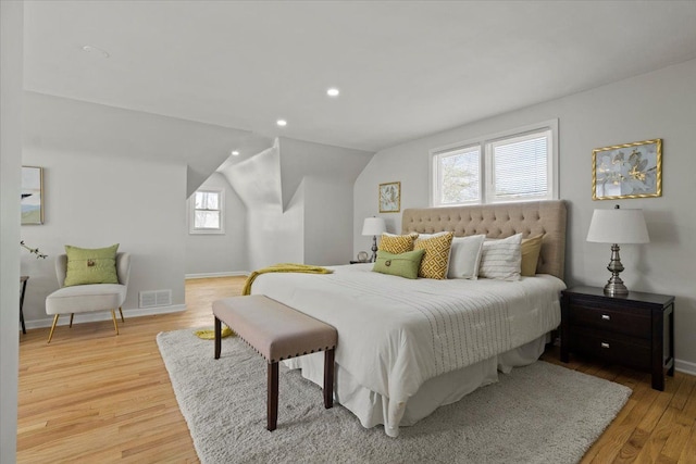 bedroom featuring visible vents, light wood finished floors, baseboards, and vaulted ceiling
