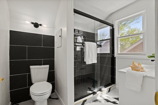 full bath with tile walls, a shower stall, and toilet
