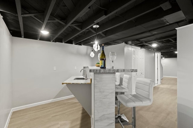 interior space featuring a sink, baseboards, light wood finished floors, and wet bar