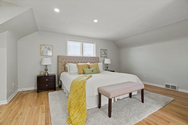 bedroom with baseboards, visible vents, lofted ceiling, and light wood-type flooring