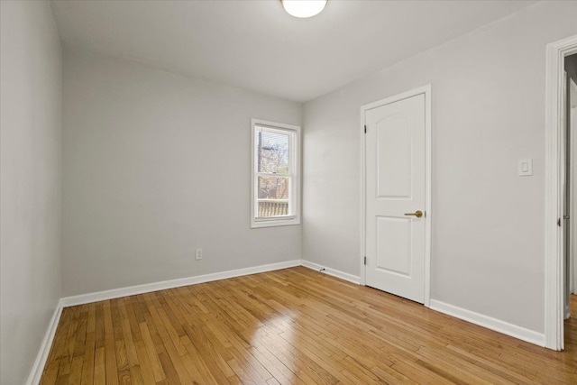 spare room with baseboards and light wood-style flooring