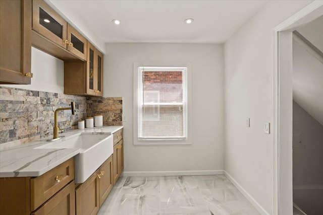 kitchen with decorative backsplash, marble finish floor, glass insert cabinets, recessed lighting, and a sink