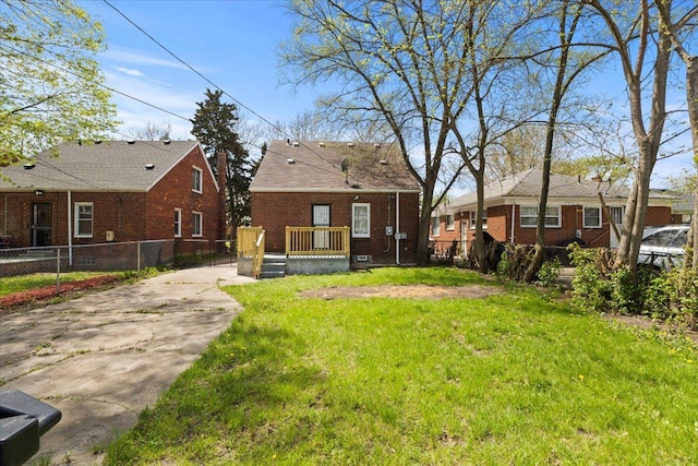 exterior space featuring fence, driveway, a front lawn, and brick siding