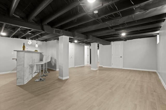 finished basement featuring baseboards, a dry bar, wood finished floors, and visible vents
