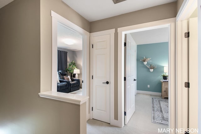 hallway featuring baseboards and light colored carpet