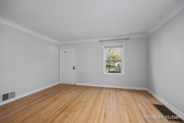 empty room featuring baseboards, visible vents, and wood finished floors
