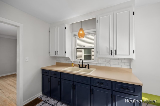 kitchen featuring a sink, white cabinetry, backsplash, and blue cabinetry
