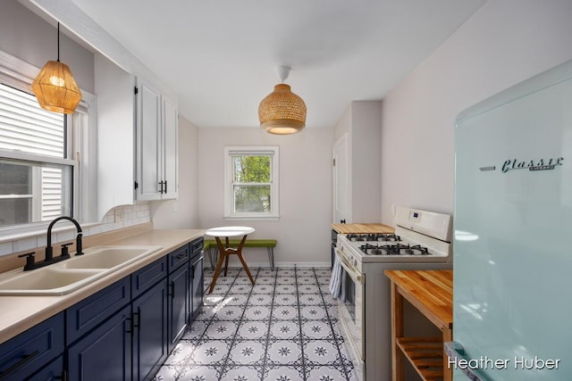 kitchen with blue cabinets, a sink, white cabinets, light floors, and white appliances