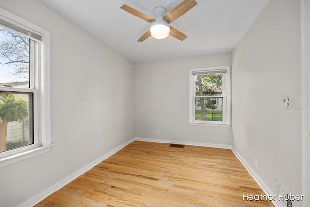 spare room featuring visible vents, a ceiling fan, light wood-style flooring, and baseboards