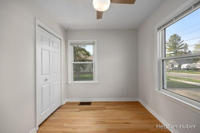 unfurnished bedroom with a ceiling fan, visible vents, light wood-type flooring, baseboards, and a closet