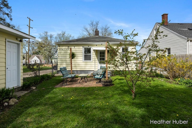 rear view of property featuring a yard, fence, a chimney, and a patio area