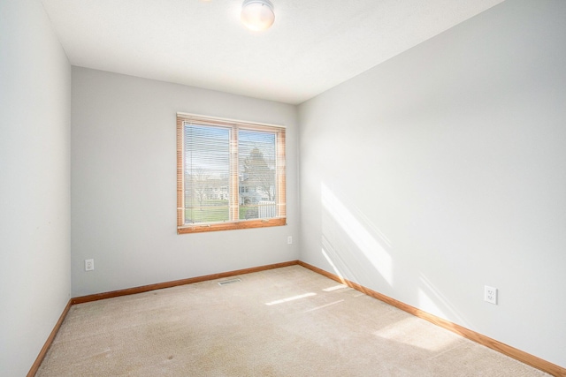 unfurnished room with baseboards, light colored carpet, and visible vents