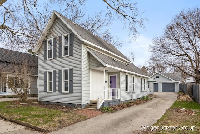 view of front of property with a garage, fence, an outbuilding, and a shingled roof