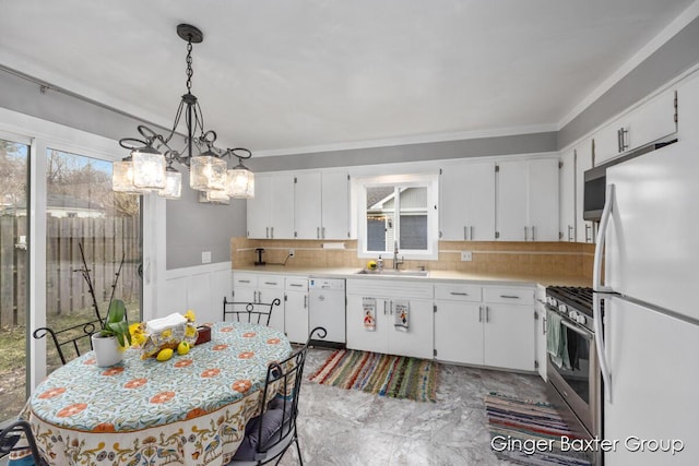 kitchen with a sink, light countertops, white cabinets, and white appliances