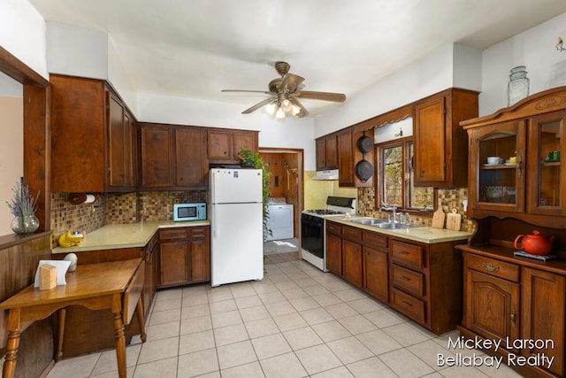 kitchen with gas range, a sink, freestanding refrigerator, stainless steel microwave, and under cabinet range hood