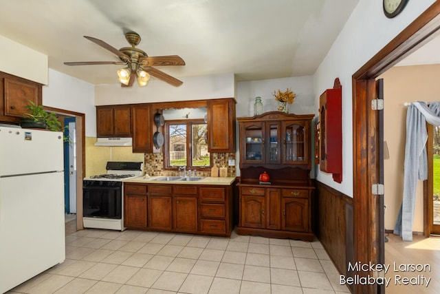 kitchen with range with gas stovetop, freestanding refrigerator, a ceiling fan, under cabinet range hood, and a sink