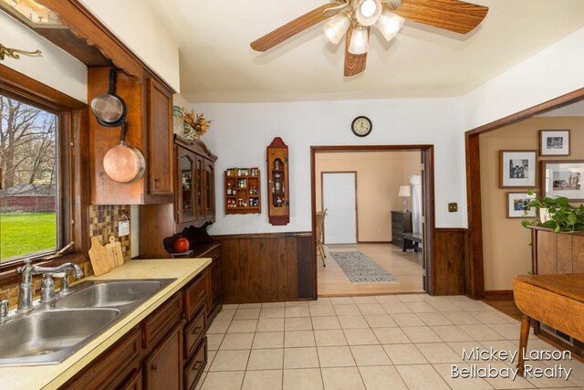 kitchen featuring a ceiling fan, wainscoting, a sink, and plenty of natural light