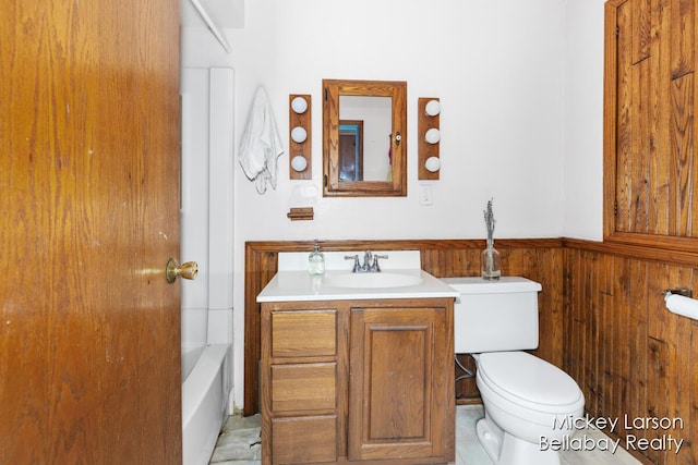 bathroom featuring a wainscoted wall, a bathing tub, vanity, toilet, and wooden walls