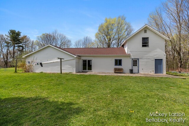 back of house with a patio, a shingled roof, and a yard
