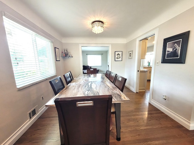 dining area with a chandelier, baseboards, visible vents, and dark wood-type flooring