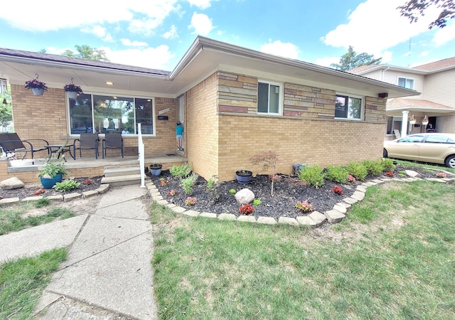 ranch-style home featuring a porch, a front yard, and brick siding