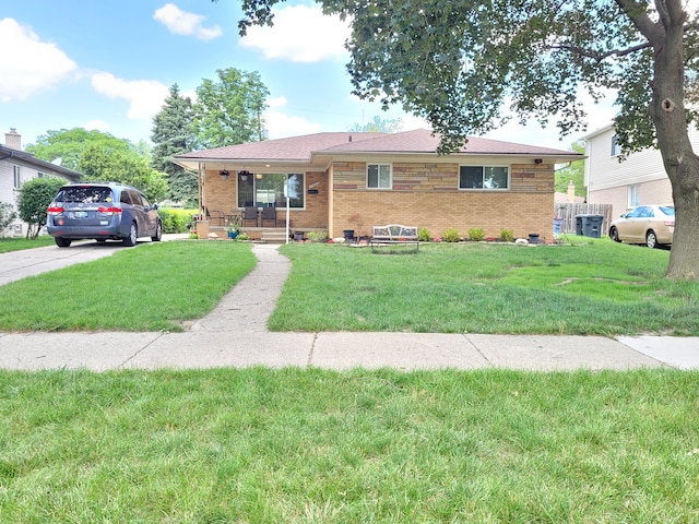 ranch-style house featuring covered porch, brick siding, and a front yard
