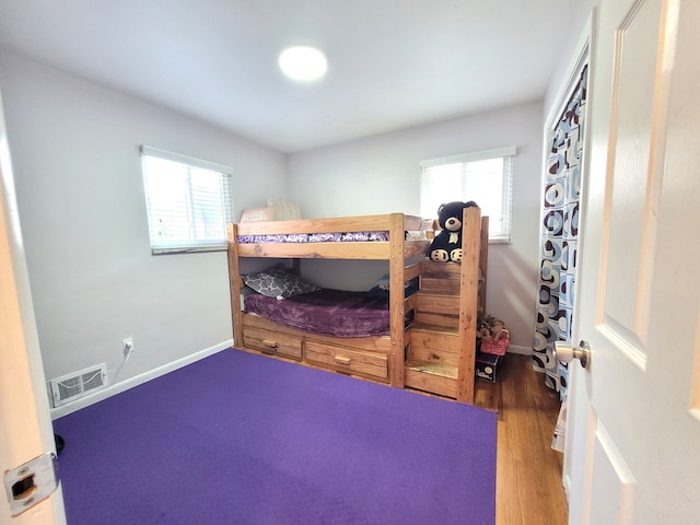 bedroom featuring visible vents, baseboards, and wood finished floors