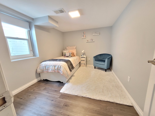 bedroom with visible vents, baseboards, and wood finished floors