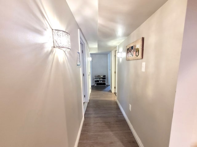 corridor with baseboards and dark wood-style flooring