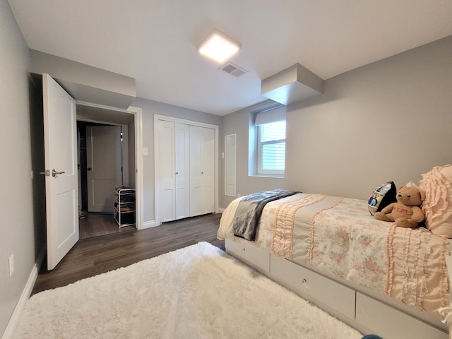bedroom with visible vents, baseboards, dark wood finished floors, and a closet