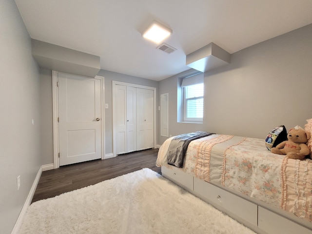 bedroom with a closet, baseboards, dark wood-type flooring, and visible vents