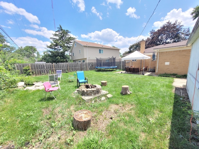 view of yard with a patio, a fenced backyard, a trampoline, and an outdoor fire pit