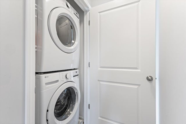 washroom featuring stacked washer and clothes dryer and laundry area