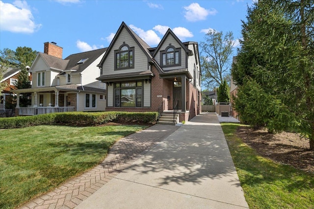 view of front of house with brick siding, fence, a front yard, and a porch
