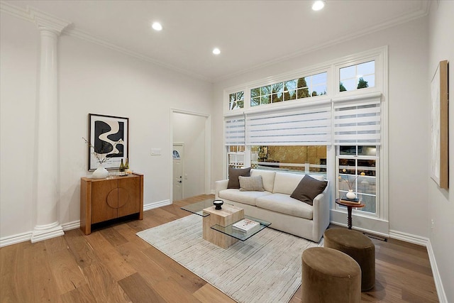 living area with ornamental molding, decorative columns, and wood finished floors
