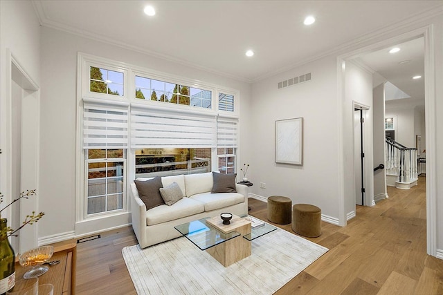living room featuring baseboards, visible vents, ornamental molding, and light wood finished floors