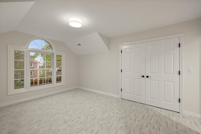 additional living space featuring baseboards, visible vents, and lofted ceiling