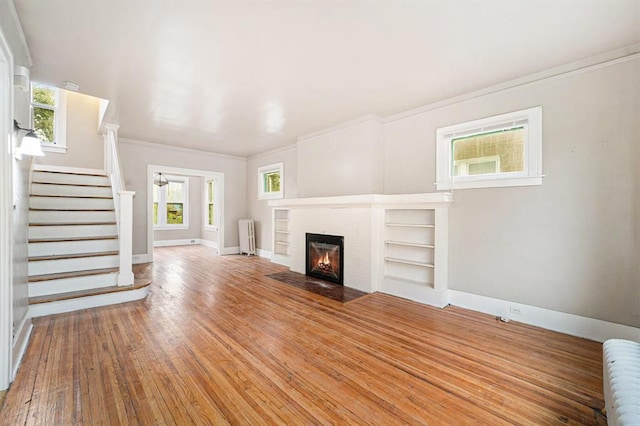unfurnished living room featuring crown molding, stairs, baseboards, and radiator heating unit