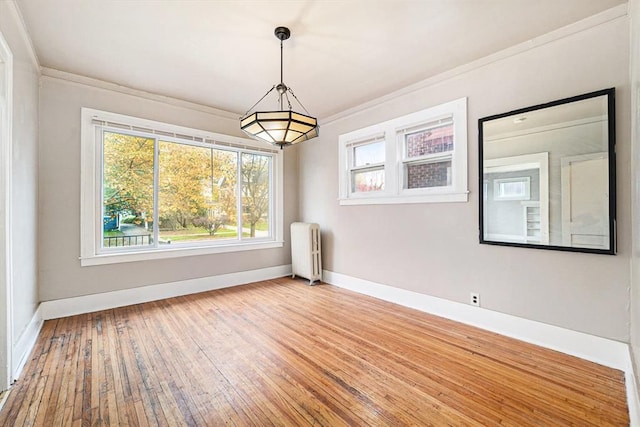 unfurnished dining area with ornamental molding, wood-type flooring, baseboards, and radiator heating unit
