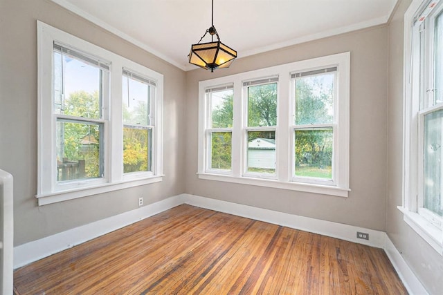 unfurnished dining area with baseboards, ornamental molding, and wood finished floors