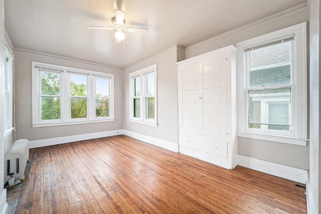 interior space with baseboards, hardwood / wood-style floors, radiator heating unit, and crown molding