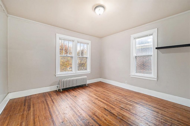 unfurnished room with crown molding, radiator, hardwood / wood-style floors, and plenty of natural light