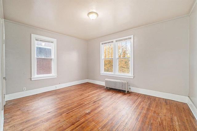 empty room with ornamental molding, radiator, wood-type flooring, and a healthy amount of sunlight