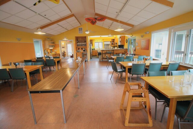dining area featuring a drop ceiling, a healthy amount of sunlight, and lofted ceiling