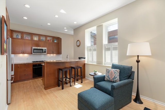 kitchen with glass insert cabinets, a breakfast bar area, brown cabinets, and stainless steel appliances