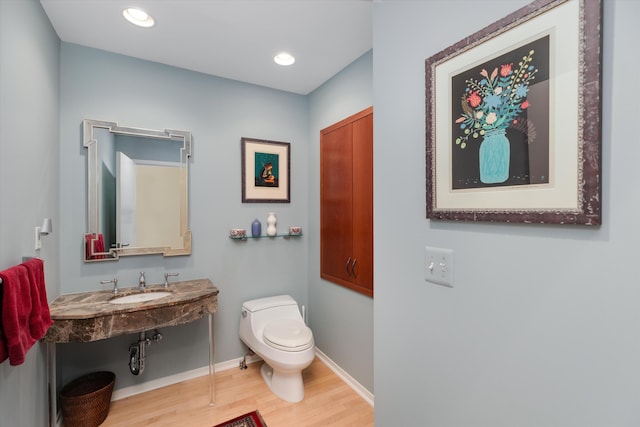 bathroom with wood finished floors, a sink, baseboards, toilet, and recessed lighting