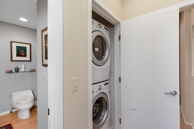washroom featuring laundry area, recessed lighting, baseboards, wood finished floors, and stacked washer and clothes dryer